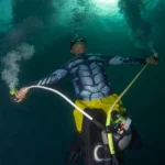 Scuba diver performing triple bubble pose with mouth, primary reg, and octo in Tioman Island