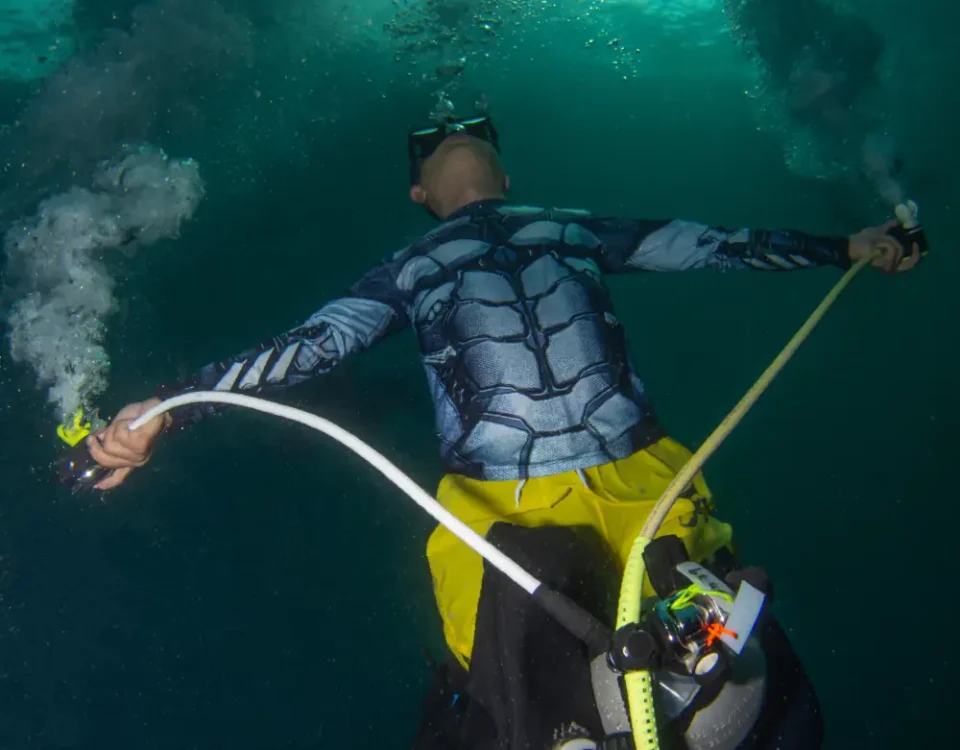 Scuba diver performing triple bubble pose with mouth, primary reg, and octo in Tioman Island