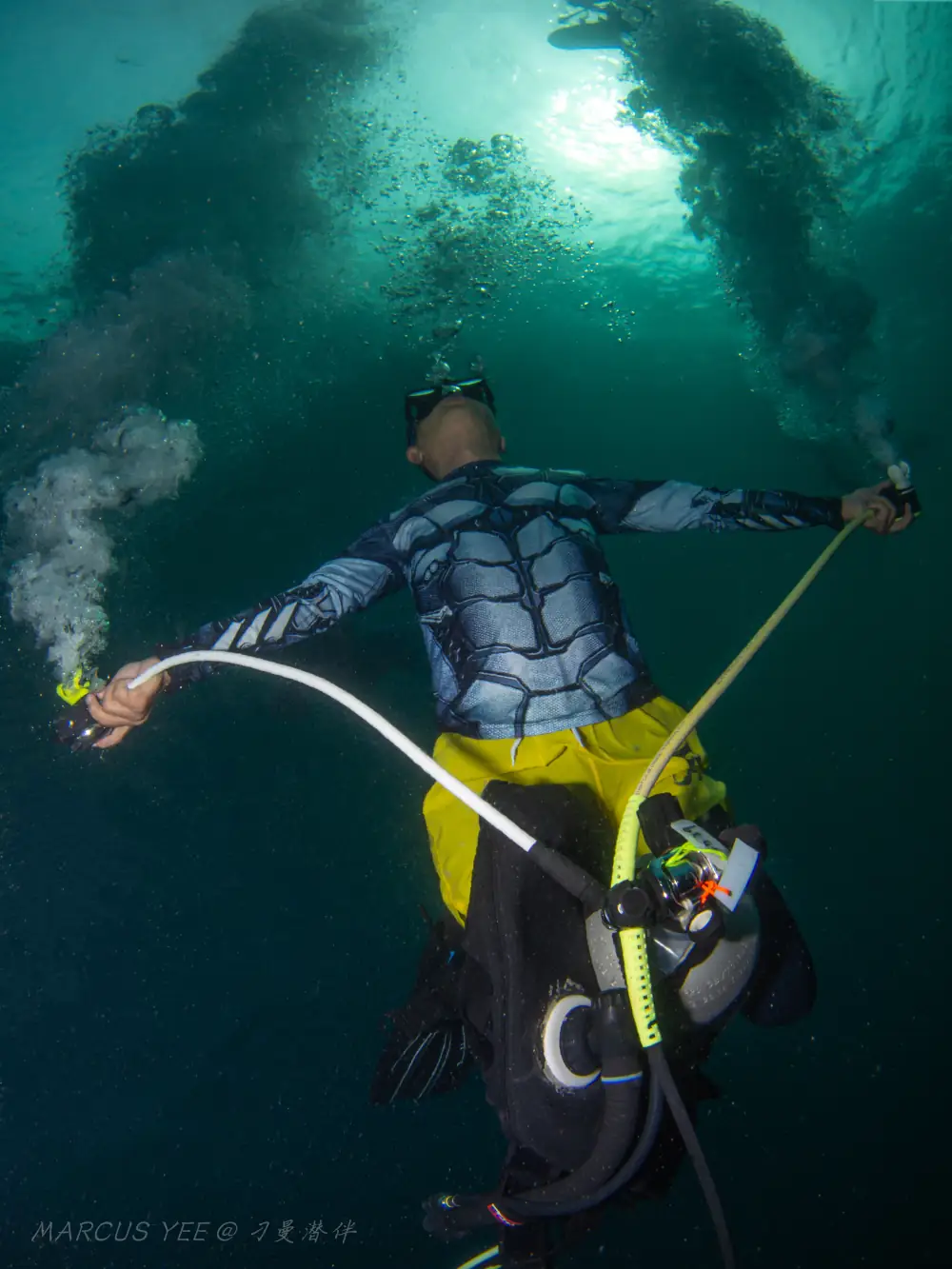 Scuba diver performing triple bubble pose with mouth, primary reg, and octo in Tioman Island